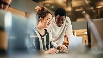 female and male colleague looking at laptop screen