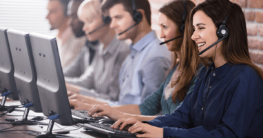 Team of 6 sales representatives at a computer desk making phone calls via their headset