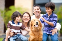 Family outdoors with a dog looking very happy